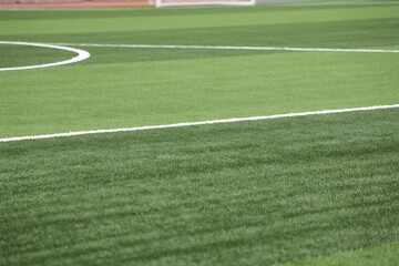 Obraz premium Close up view of a vibrant green artificial turf soccer field with white markings for athletic usage.