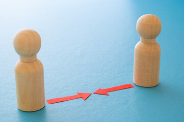 Concept of conflict I war between people or groups. Wooden figures gathered in two groups facing each other.