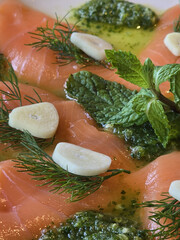 Fresh salmon fillet garnished with herbs, garlic, and mint, drizzled with olive oil. vibrant and appetizing dish perfect for seafood lovers