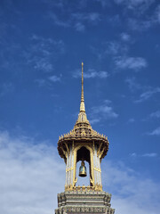 stunning temple spire reaching towards blue sky, adorned with intricate details and bell. architecture reflects cultural heritage and craftsmanship