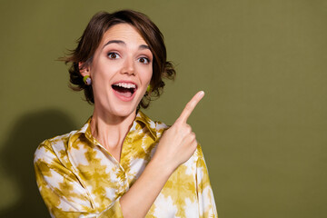 Young businesswoman in an elegant blouse pointing with excitement against a khaki background