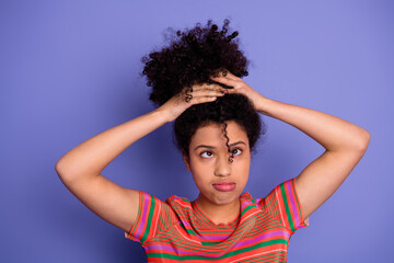 Young woman with curly hairstyle making a thoughtful gesture against purple background, expressing...