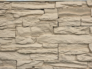 Textured beige stone wall with natural, rugged appearance, ideal for architectural designs and landscaping. uneven surfaces create visually appealing backdrop
