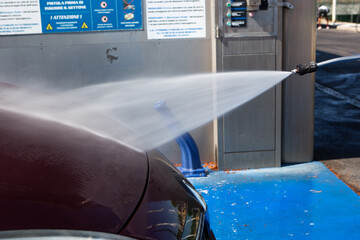 Car being professionally washed at self service station powerful water stream cleaning vehicle...