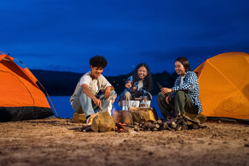 Three people sitting around a fire in a campsite. Group of friends enjoy outdoor camping, a celebration of friendship, connection, and togetherness around a campfire.