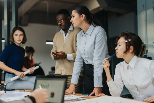 A diverse group of business people of different ages engaged in a brainstorming session, fostering teamwork and creativity in a modern office environment.
