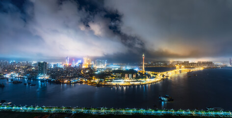 Panoramic view of the illuminated Macau peninsula cityscape with its famous tower and surrounding...