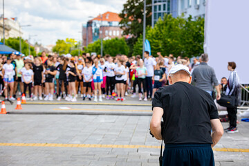 Photographer is taking photo of large group of athletes waiting at marathon start line