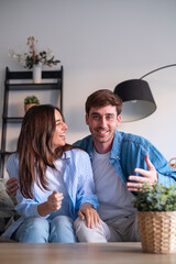 Smiling couple sitting together on a sofa, appearing happy and relieved after resolving...