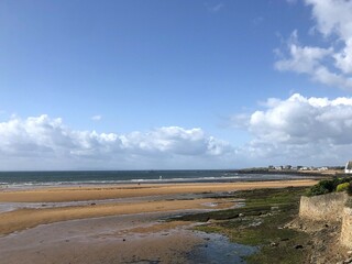 Authentic Coastal Scene with Wet Sand, Seaweed and Remote Hamlet under Overcast Skies, Natural Shoreline Capturing the Rugged Beauty of the British Isles