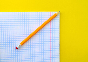 White notebook in a cage and a pencil on a yellow background.