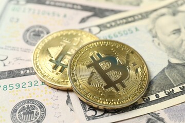 Close up of metal shiny bitcoin crypto currency coins on US dollar bills. Electronic decentralized money concept. 