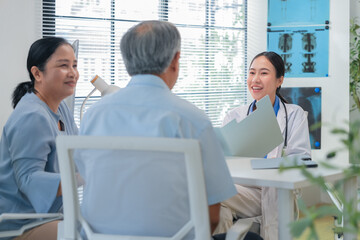 Asian doctor in uniform attentively assists a senior couple with medical paperwork in a hospital area, explaining health records and test results with care and professionalis senior health