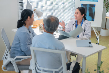 Asian doctor in uniform attentively assists a senior couple with medical paperwork in a hospital area, explaining health records and test results with care and professionalis senior health
