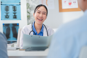 Asian doctor in uniform attentively assists a senior couple with medical paperwork in a hospital area, explaining health records and test results with care and professionalis senior health