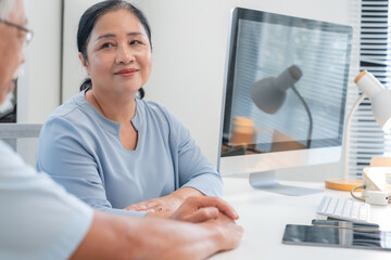 Asian doctor in uniform attentively assists a senior couple with medical paperwork in a hospital area, explaining health records and test results with care and professionalis senior health