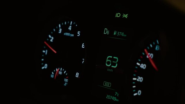 Car instrument cluster showing speed, gear D6, fuel range, and ECO mode for efficient driving. Dashboard illuminated at night, with engine RPM and temperature gauge active. Display presenting real