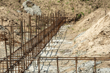 Steel reinforcement bars are lined within a prepared trench at a construction site, ready for...