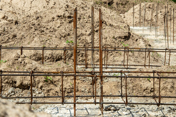 Steel reinforcement bars are set in position at a construction site, preparing for foundation work...