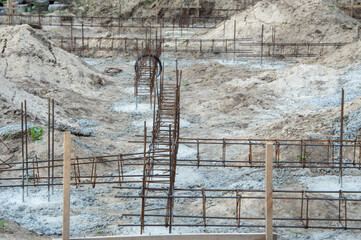 Workers prepare the foundation of a building at a construction site with visible steel bars and...
