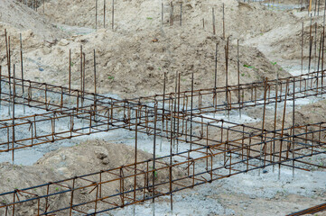 Framework for a building is laid out on a construction site. The ground is mostly bare, with mounds of dirt around the area