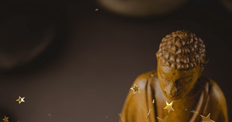 Shining carved Buddha statue radiating warm glow on display, with star-shaped confetti, copy space