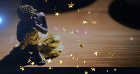 Resting seated Buddha figurine wearing golden robe on wood table at home, star overlays, copy space