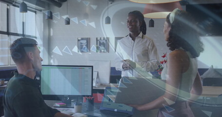 Gathering three coworkers in business attire discussing spreadsheet in office, with laptop