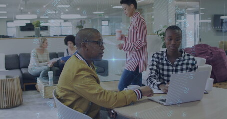 Collaborating man in mustard jacket and woman in checkered top typing on laptop in office lounge