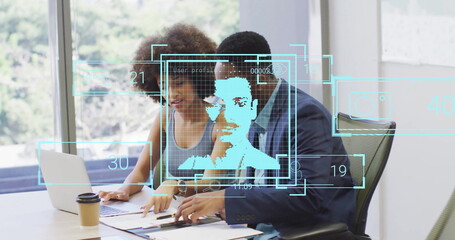 Colleagues analyzing documents and holographic overlays in office meeting room, with laptop