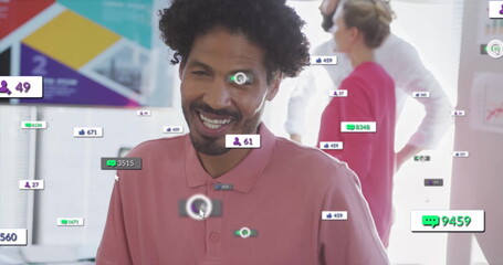 Smiling adult man wearing pink polo shirt sitting at desk in office, showing social media metrics