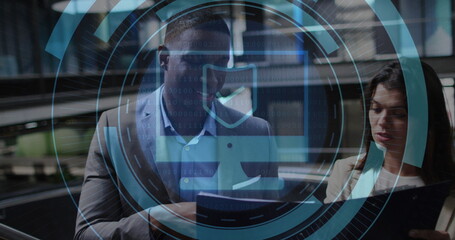 Reviewing tablet and printouts by team in business attire in office hallway, cybersecurity overlay