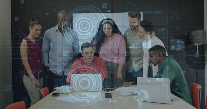 Collaborating seven professionals examining holographic overlay at conference table, with laptops