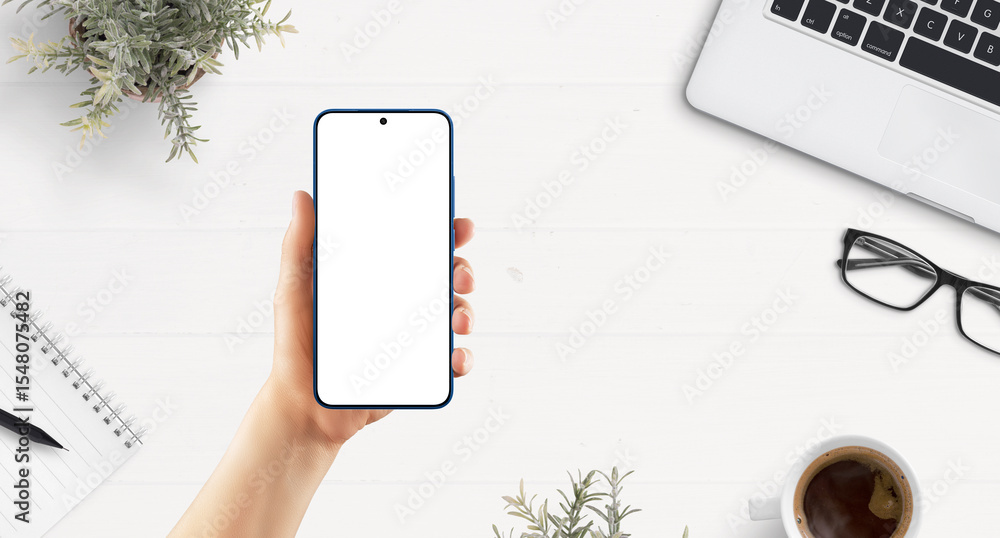 Poster top view of smartphone in female hand over white desk with laptop, coffee, notebook, and workspace i