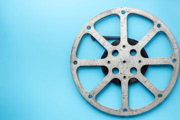 Obraz premium Old 35mm motion picture film reel on blue background. Cinema concept