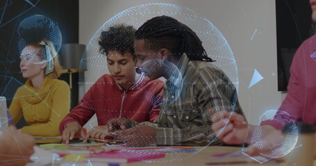 Collaborating team pointing at sticky notes and writing in meeting room with globe overlay