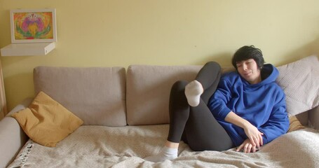 A young woman lounges on a couch, casually talking on her cell phone with crossed legs, exuding relaxation and connection in everyday life - Powered by Adobe