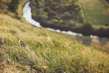 Tranquil summer afternoon by the serene river, where lush green hills meet gentle flowing waters in a peaceful landscape