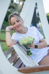 A young, beautiful girl with a bouquet of lilies of the valley on a walk.