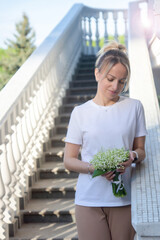 A young, beautiful girl with a bouquet of lilies of the valley on a walk.