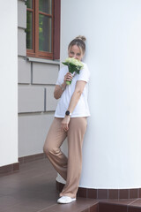 A young, beautiful girl with a bouquet of lilies of the valley on a walk.