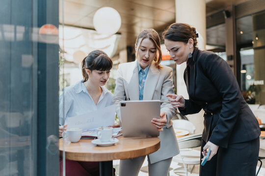 Businesswomen working together and discussing ideas in a relaxed coffee shop setting.