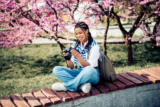 Cute Young woman enjoying photography in blooming park during sunny spring day