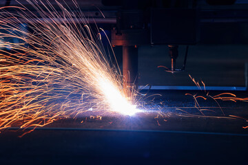 Plasma cutting machine cuts metal material with sparks, industrial background