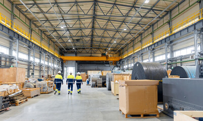 Group of warehouse workers wearing hard hats and reflective jackets uniform waking in industrial...