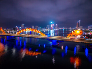 Da nang dragon bridge illuminated at night with vibrant cityscape reflections