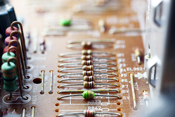 Close-up of a printed circuit board with resistors and capacitors. The board features copper traces...