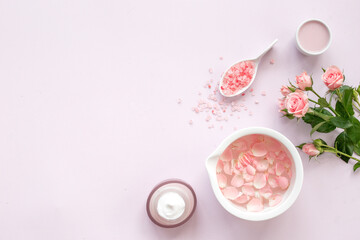 Roses essence water in bowl with petals and skin care cosmetic products with flowers essential oil