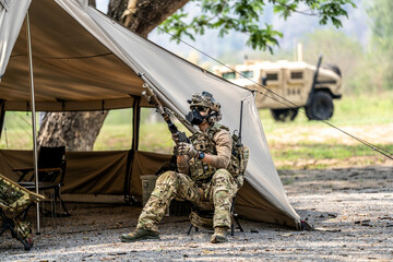 Special forces soldiers preparing tactical gear at military field base camp with weapons and...