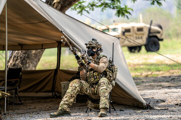 Special forces soldiers preparing tactical gear at military field base camp with weapons and...